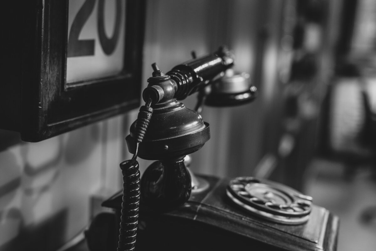 A black+white picture of an old landline telephone.